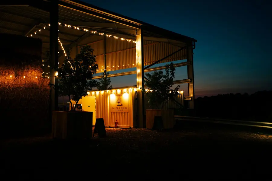The open barn lit with warm lights against a dusk sky