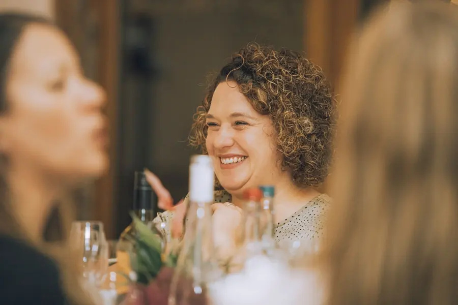 Guests laughing over dinner at a celebration in the barn