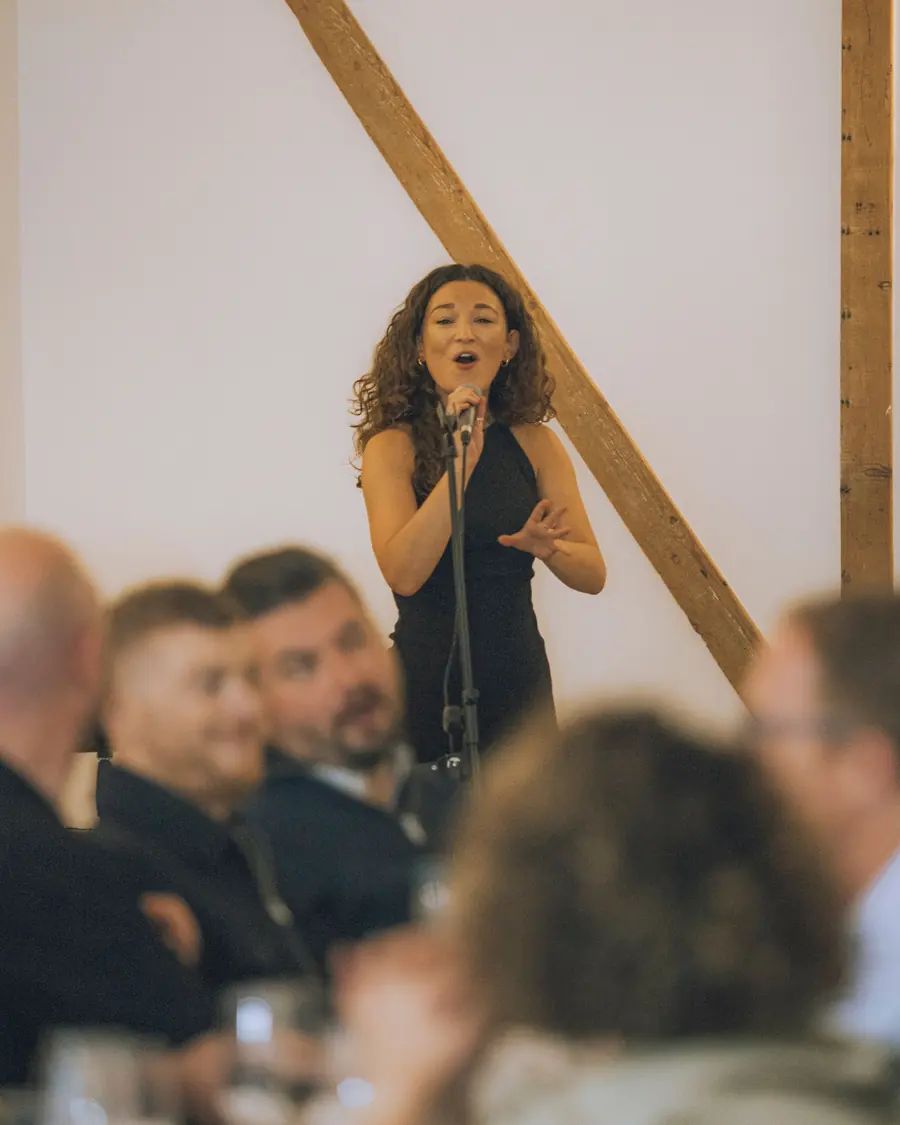 A singer performing to seated guests in the barn