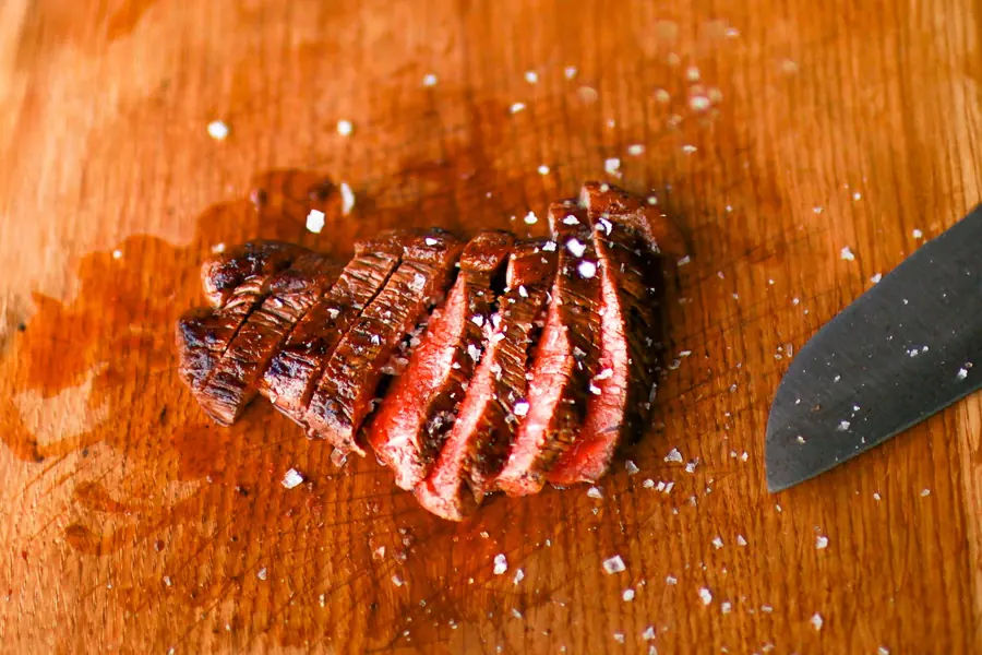 Sliced Wagyu rump steak resting on a wooden board with sea salt